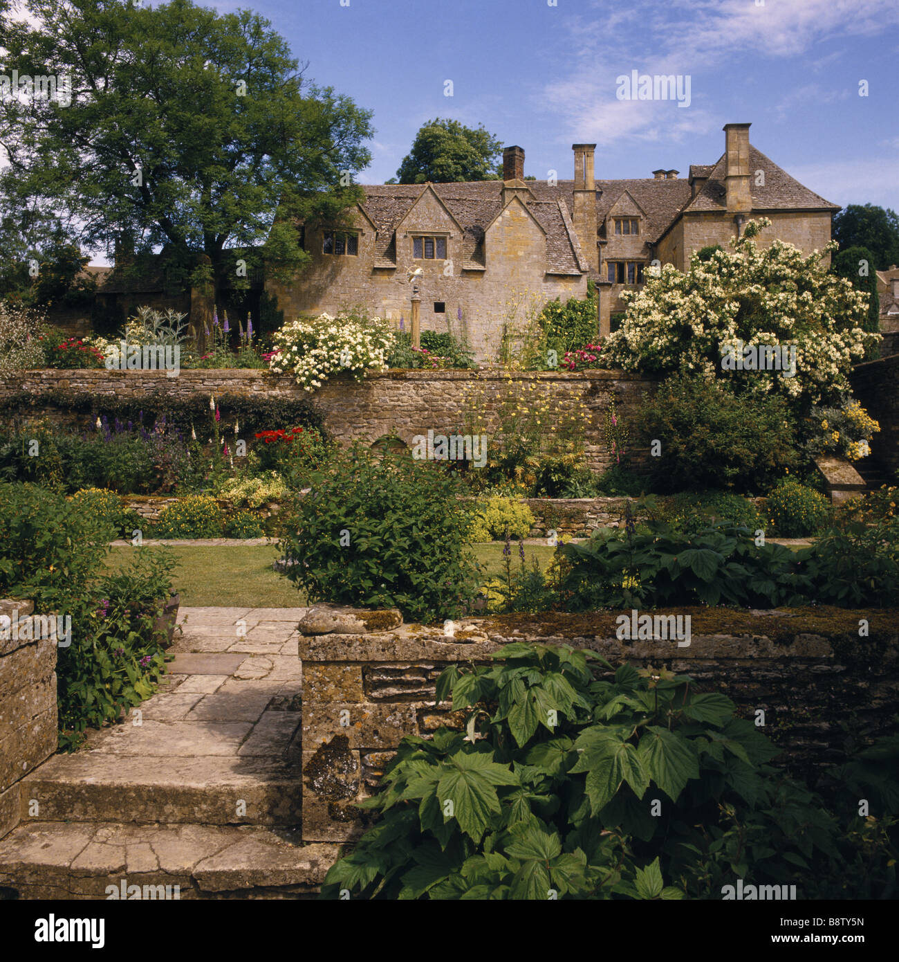 View of the west front of Snowshill Manor seen from the Well Court with flowers and foilage Stock Photo