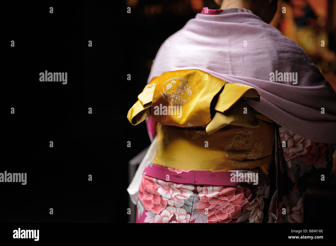 Colorful yellow obi (sash) against the background of a pink kimono