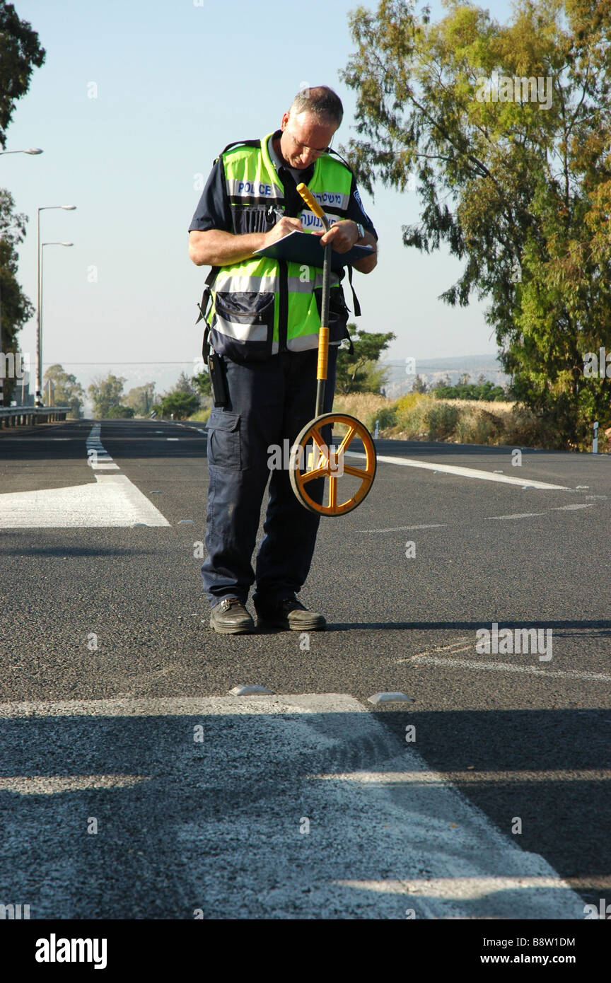 Car Accident An inspector measuring the skid marks Stock Photo