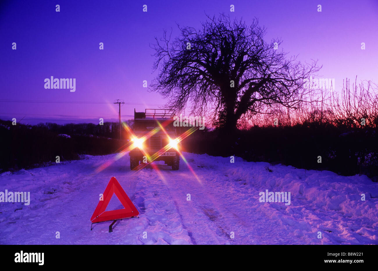 vehicle travelling down snow bound country road by hazard warning