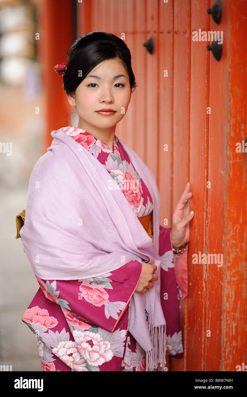 Japanese young woman in a beautiful pink kimono against an orange background - Kyoto Japan Stock Photo