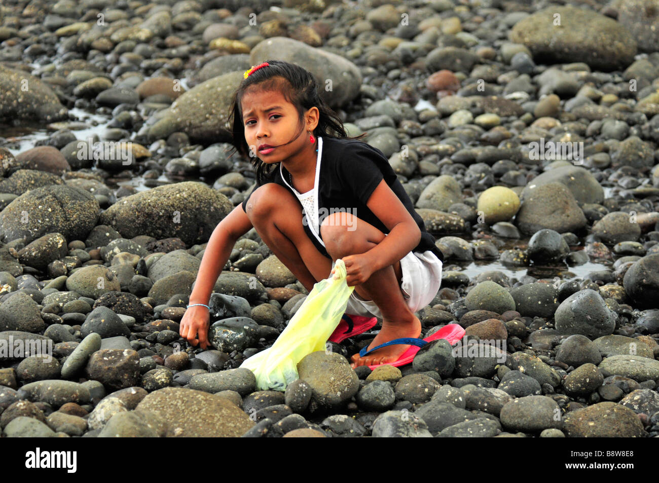 Little kid is looking for clam under the black stone,Medewi,Bali
