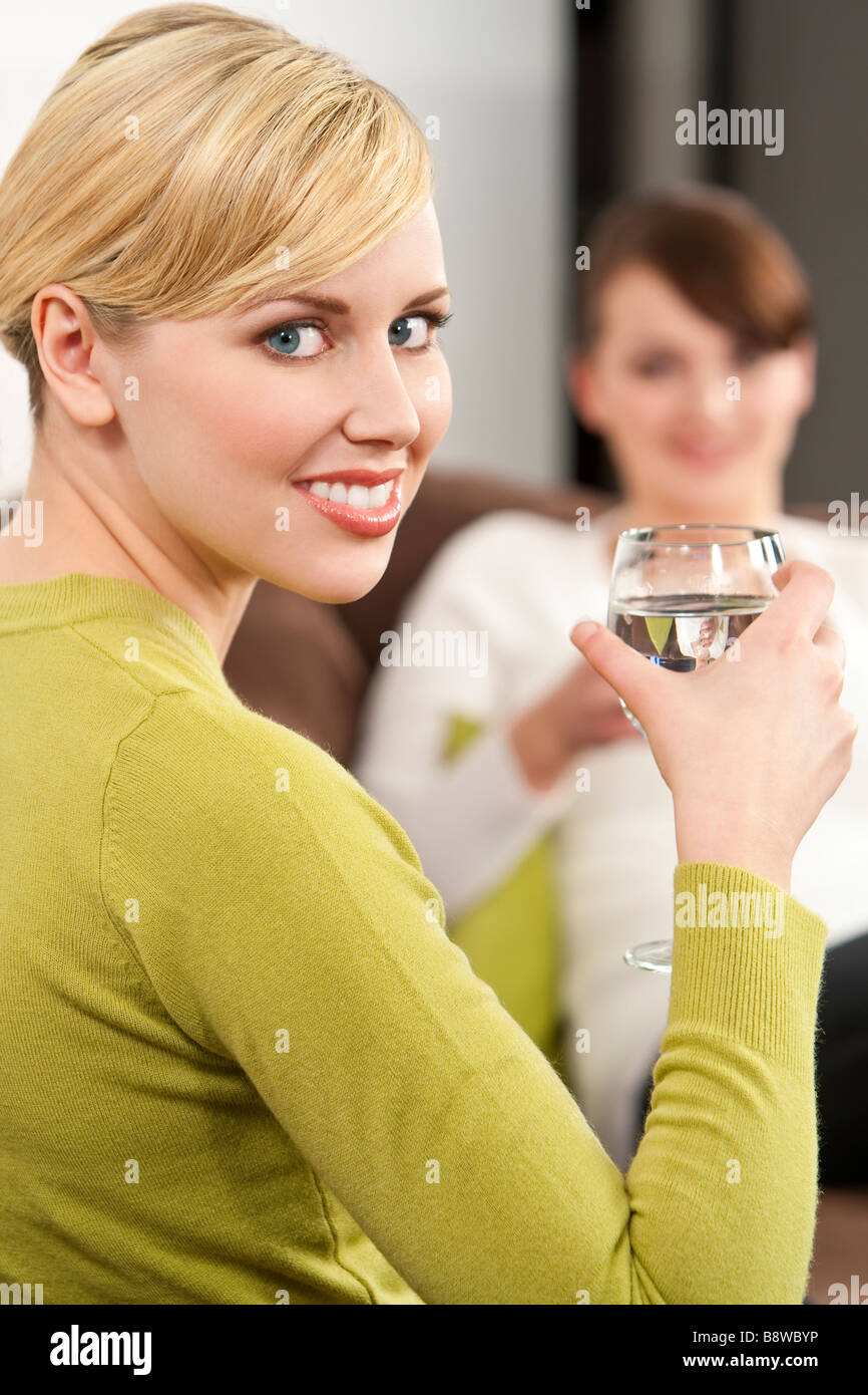 Two young women chatting while drinking glasses of mineral water Stock