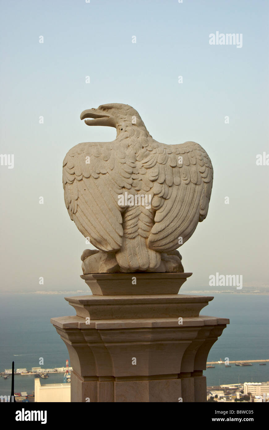 Stone eagle sculpture on parapet railing in Bahai Gardens overlooking port of Haifa on Mediterranean sea coast Stock Photo