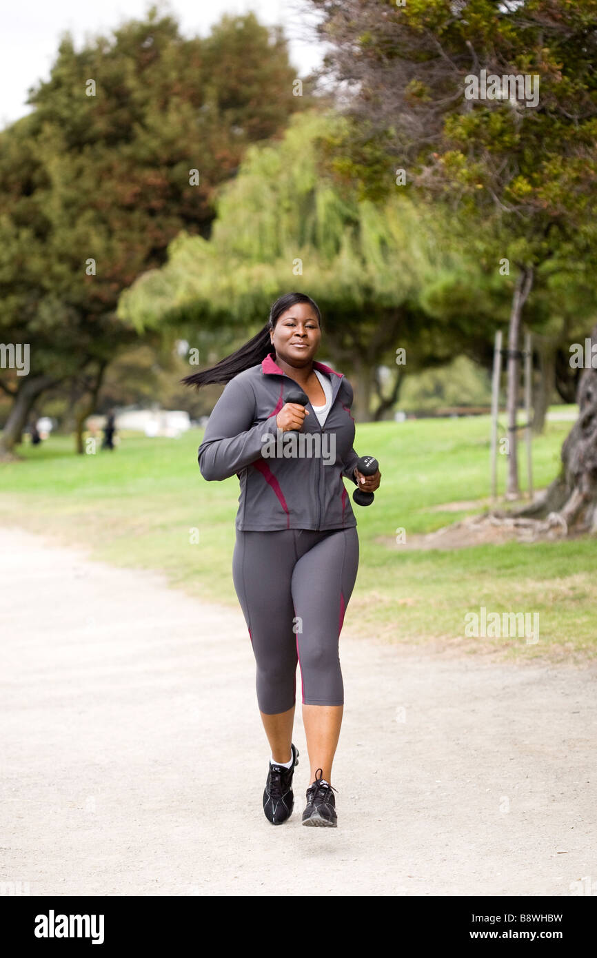 Plus size model power speed walking / jogging with hand weights Stock Photo  - Alamy