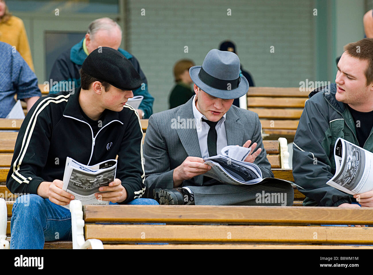 Horse Racing Bettors reading racing forms prior to race and placing wagers. Stock Photo