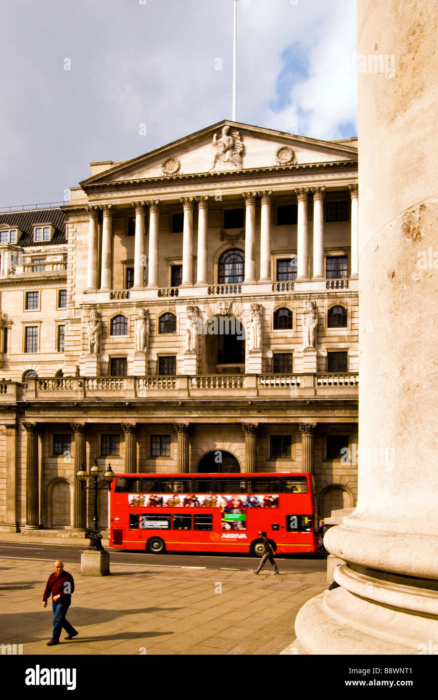 Red London bus driving past Bank of England building, UK Stock Photo