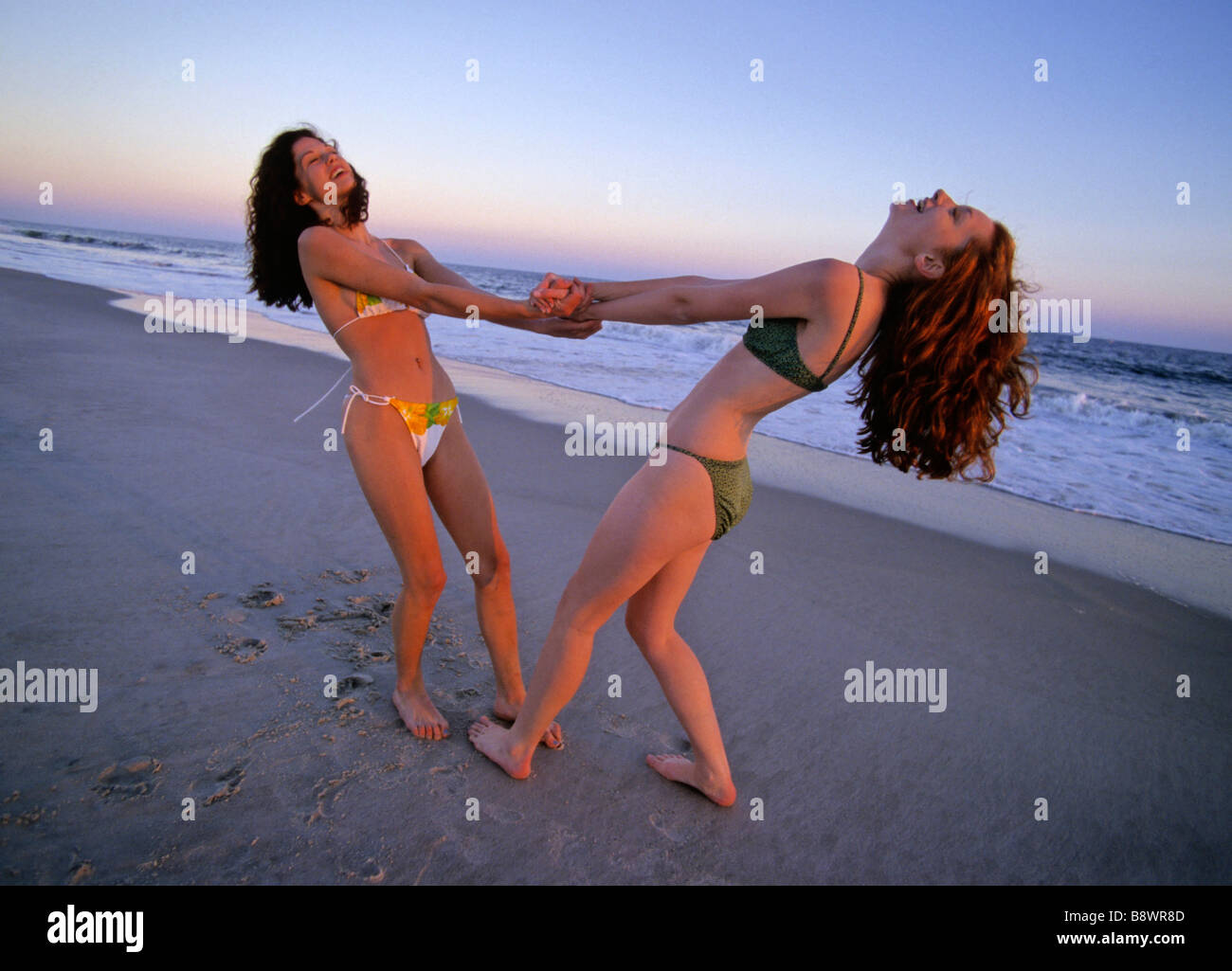 2 young girls at the beach having fun fighting Stock Photo - Alamy