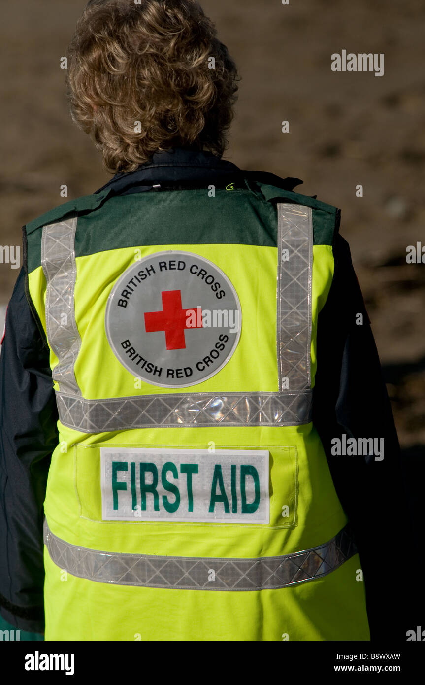First aid volunteer British Red Cross worker wearing a yellow high visibility jacket coat UK Stock Photo