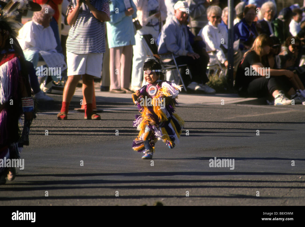 Young native American child dance street parade audience cute costume feather smile happy joy move run Stock Photo