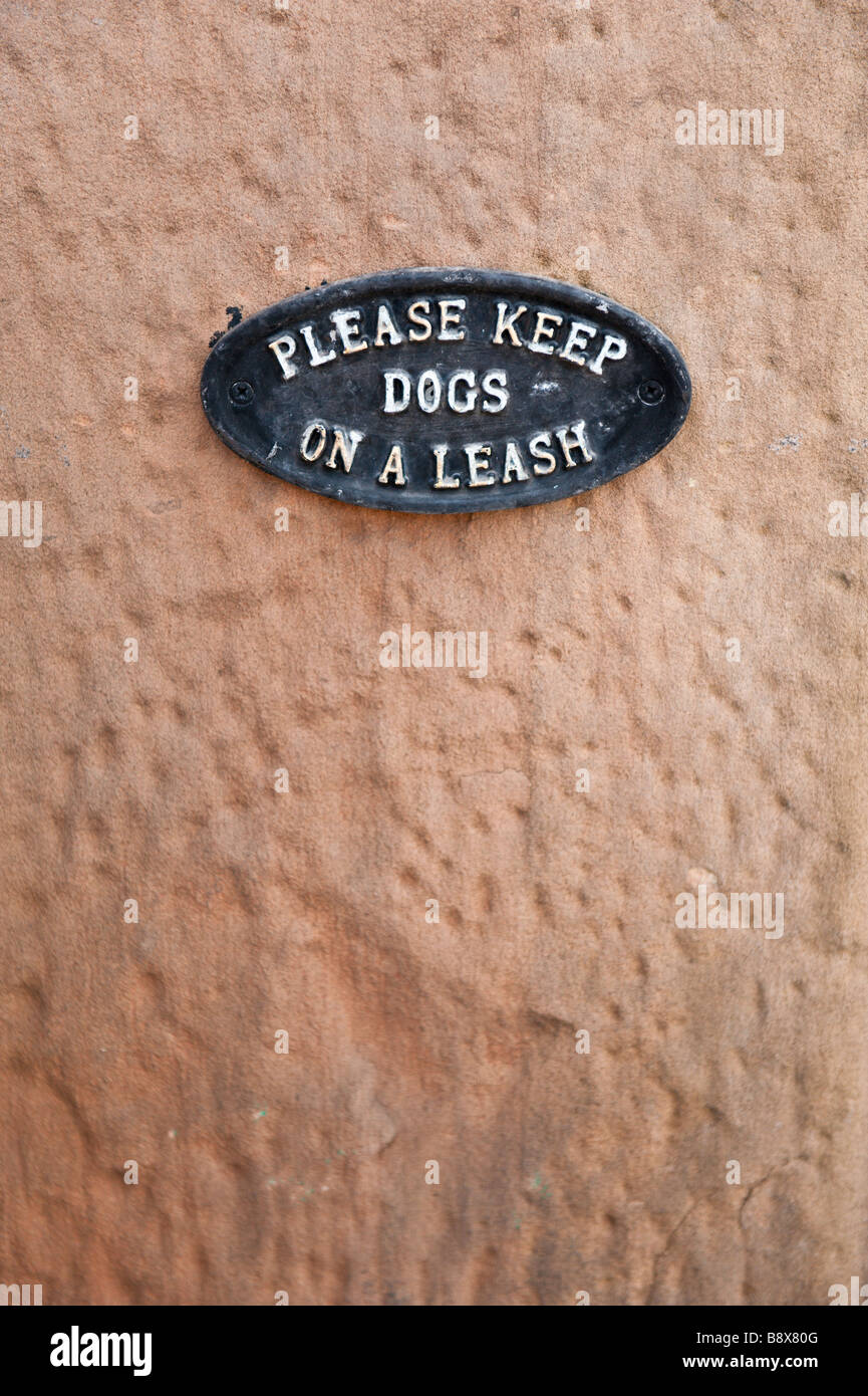 Please keep dogs on a leash. Small iron plaque sign stating the request