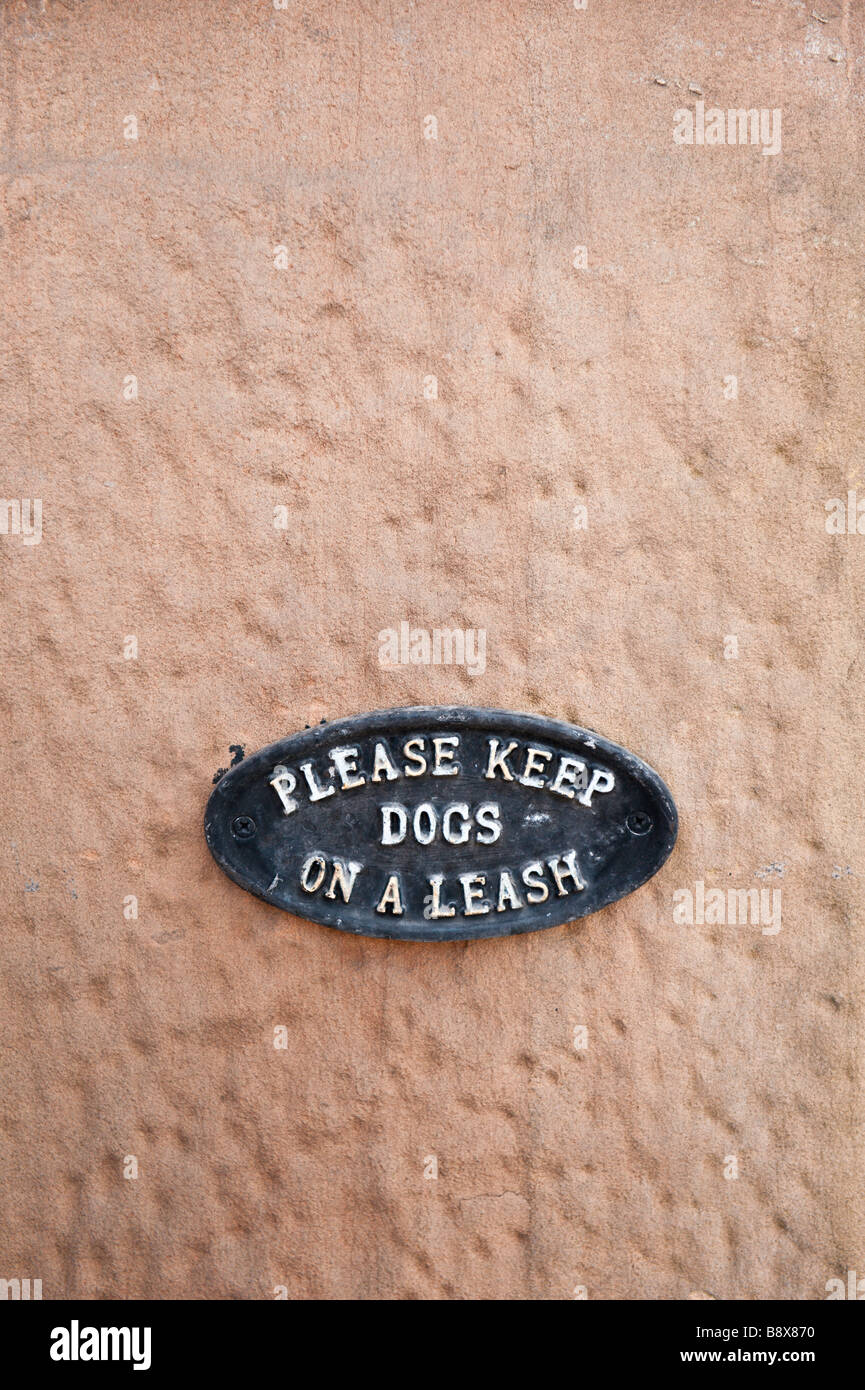 Please keep dogs on a leash. Small iron plaque sign stating the request