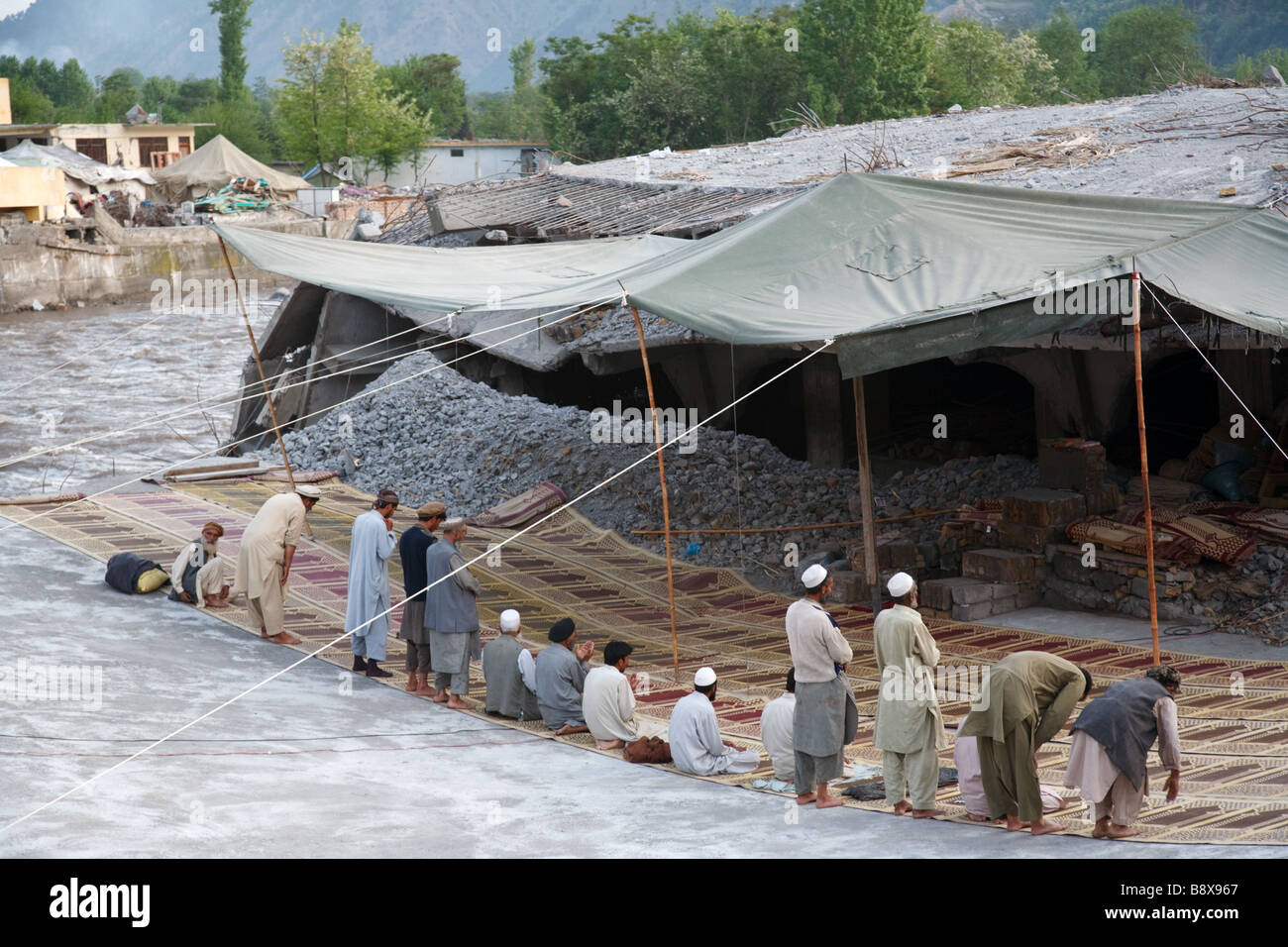 Men gather for evening prayers in the ruins of mosque in Balakot, Pakistan destroyed in the 2005 earthquake Stock Photo