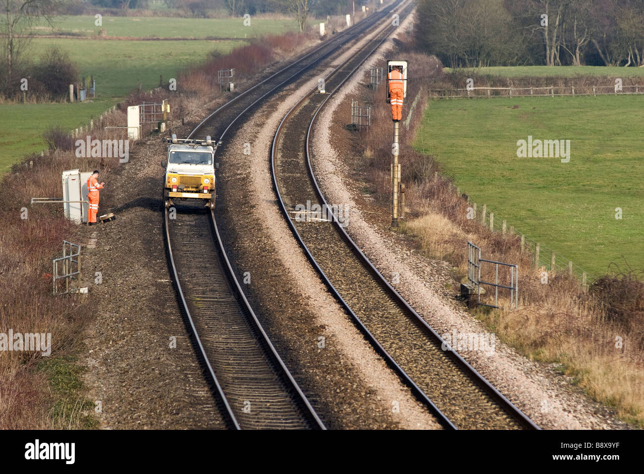 Men are repairing railway signals on a train track in Devon. Their land ...