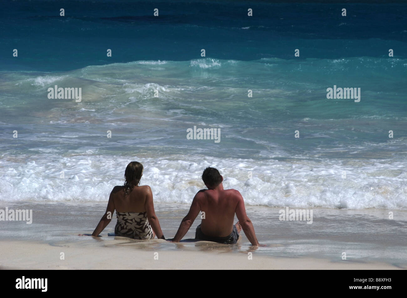 Couple Sitting in the Surf on Crane Beach Barbados Stock Photo