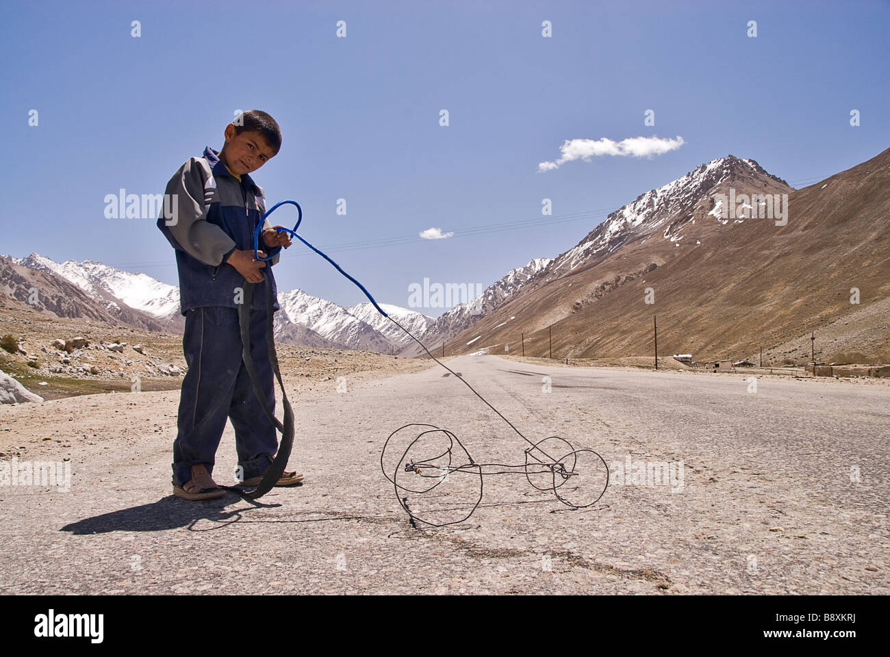 Tajik boy playing with an very basic toy, Pamir Highway, Tajikistan Stock Photo