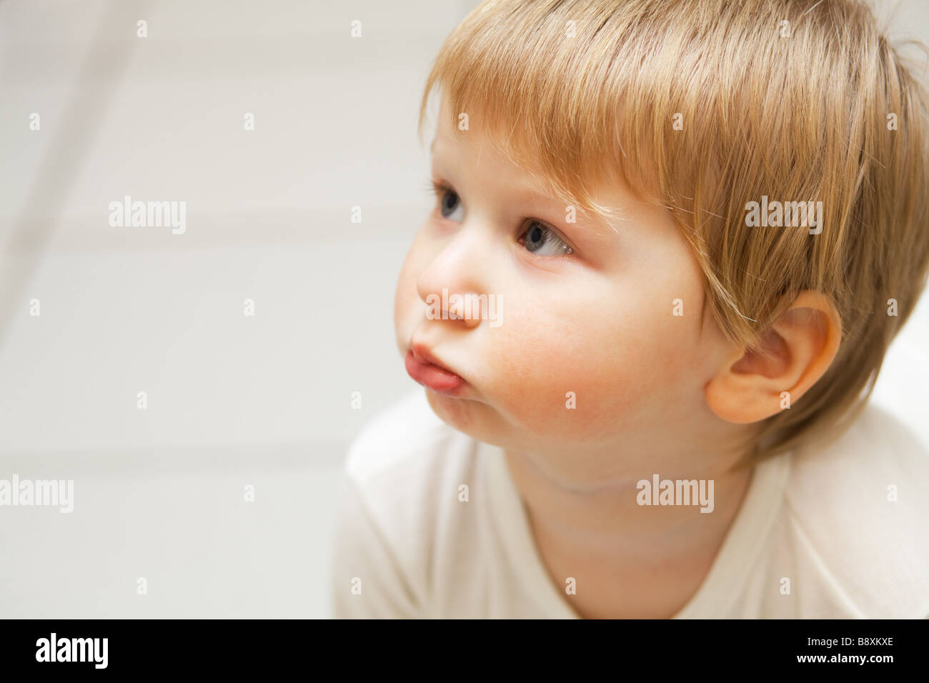 Indoor photo of little blond boy with puffed out cheeks Stock Photo