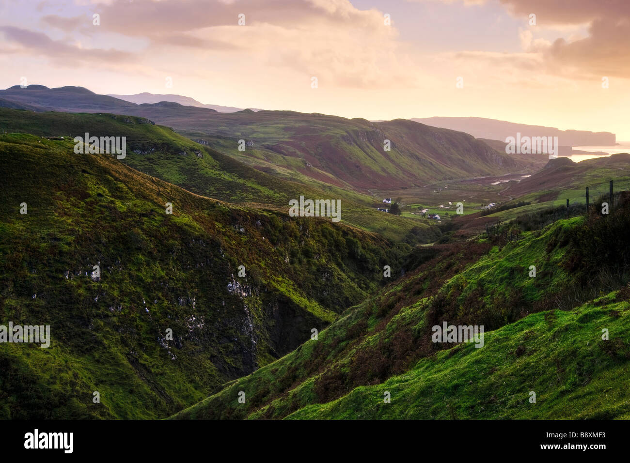 Green valley in the Scottish highlands at sunset with the ocean in the distance Stock Photo