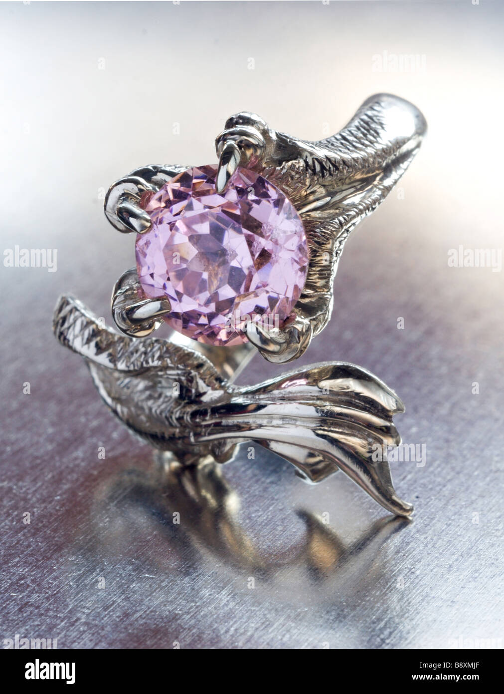 a white gold dragon ring with pink amethyst on metal background Stock Photo