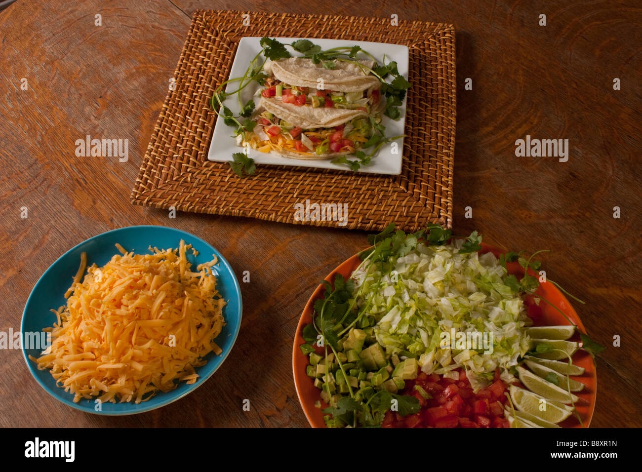 A plate of traditional style soft tacos on a bamboo charger garnished with cilantro Stock Photo