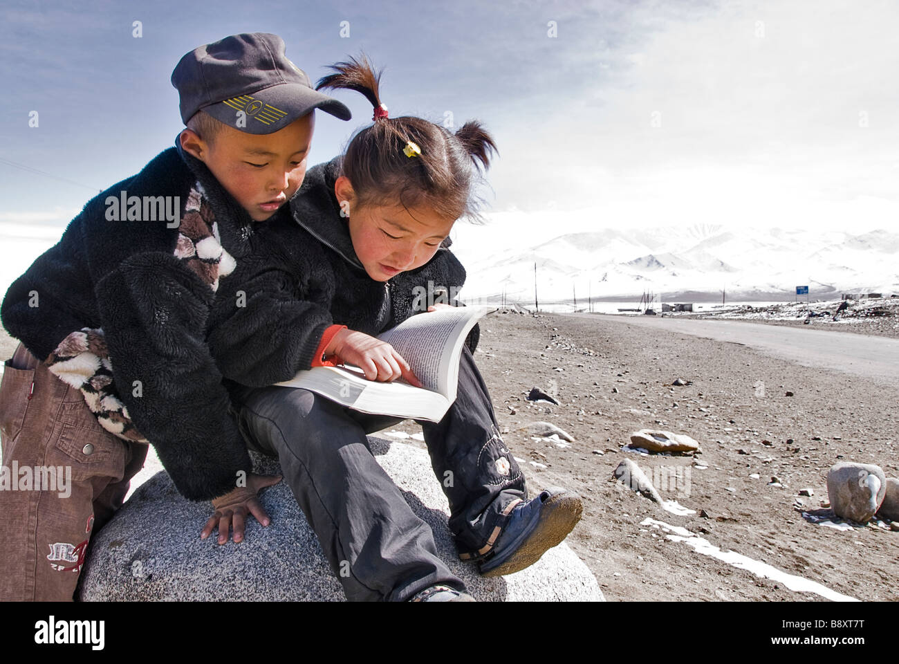 Children reading a book nar the Pamir highway, Tajikistan, Asia Stock Photo