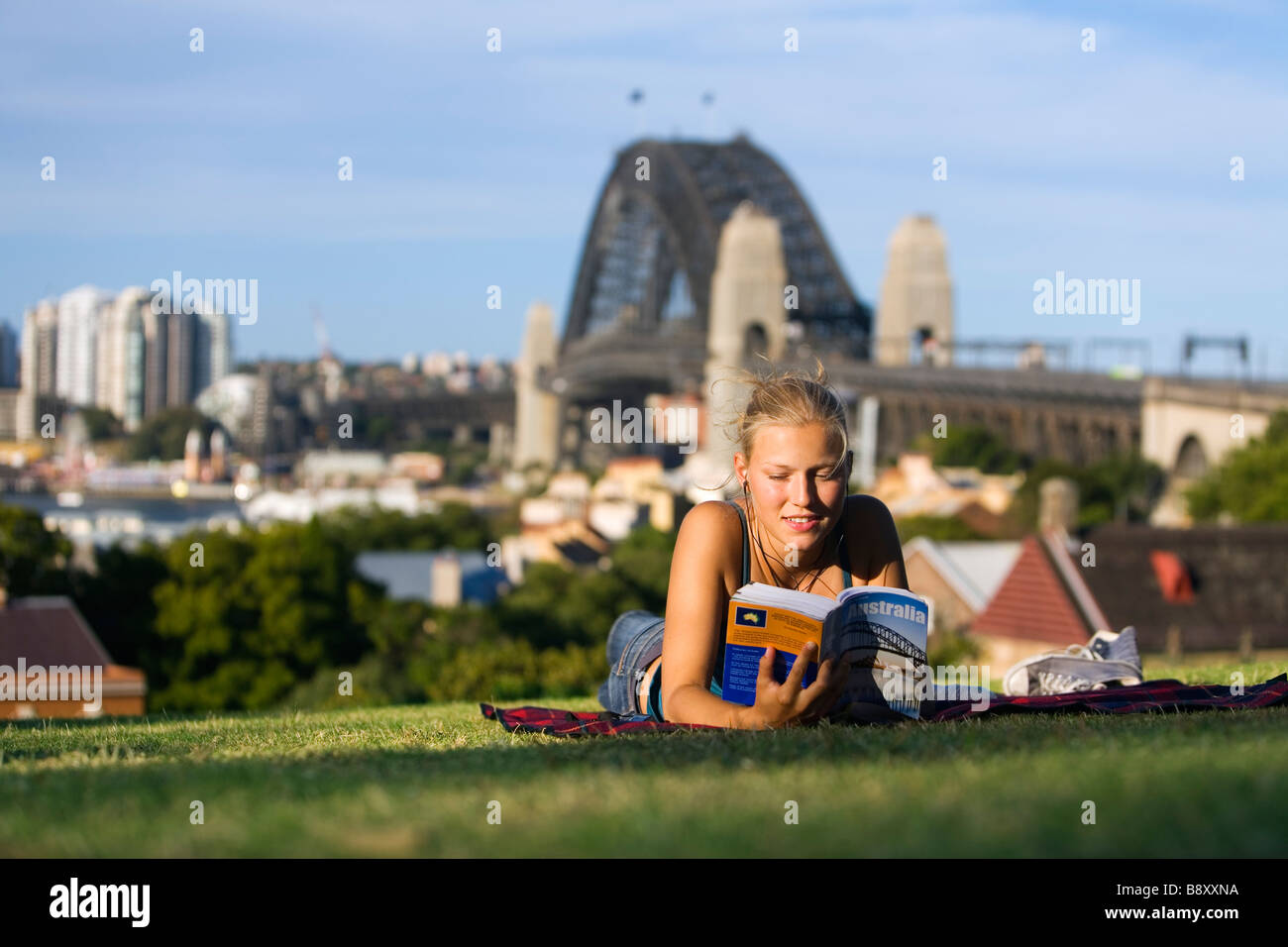 A young woman reads a guide book on Observatory Hill, overlooking Sydney harbour.  Sydney, New South Wales, AUSTRALIA Stock Photo