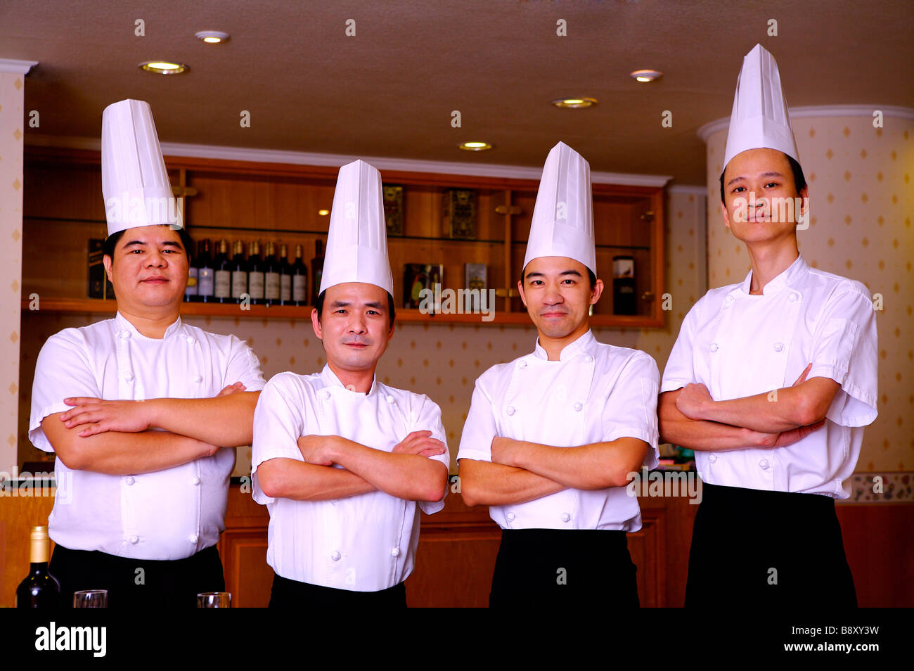 Four chef standing in a row with arms crossed and looking at the camera Stock Photo