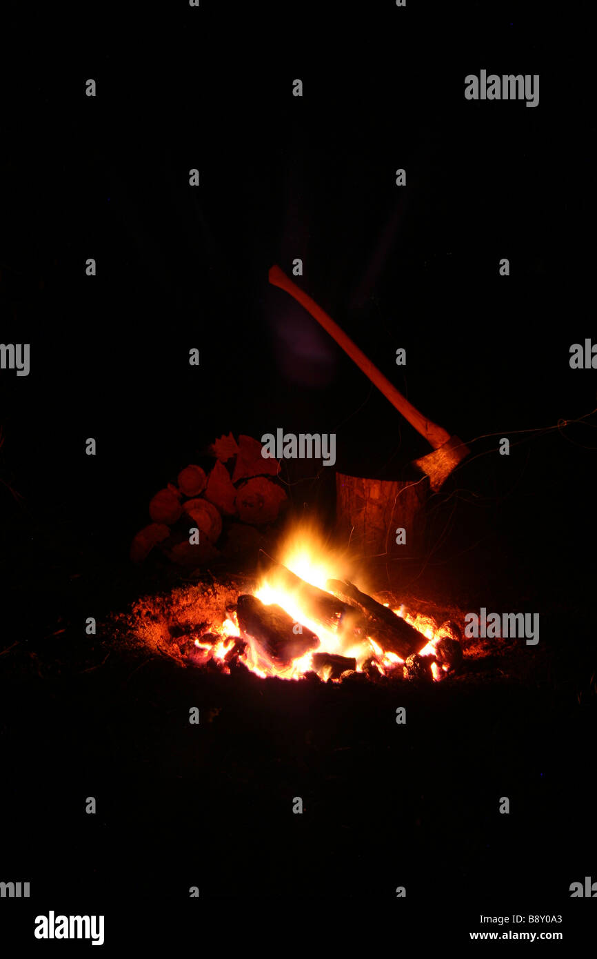 A campfire with chopped wood and axe in the background Stock Photo