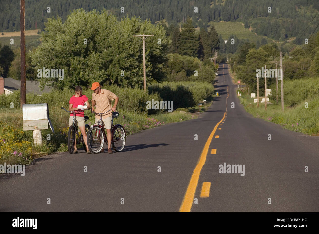 Couple reading mails by a mailbox while riding bicycles, Parkdale, Hood River County, Oregon, USA Stock Photo