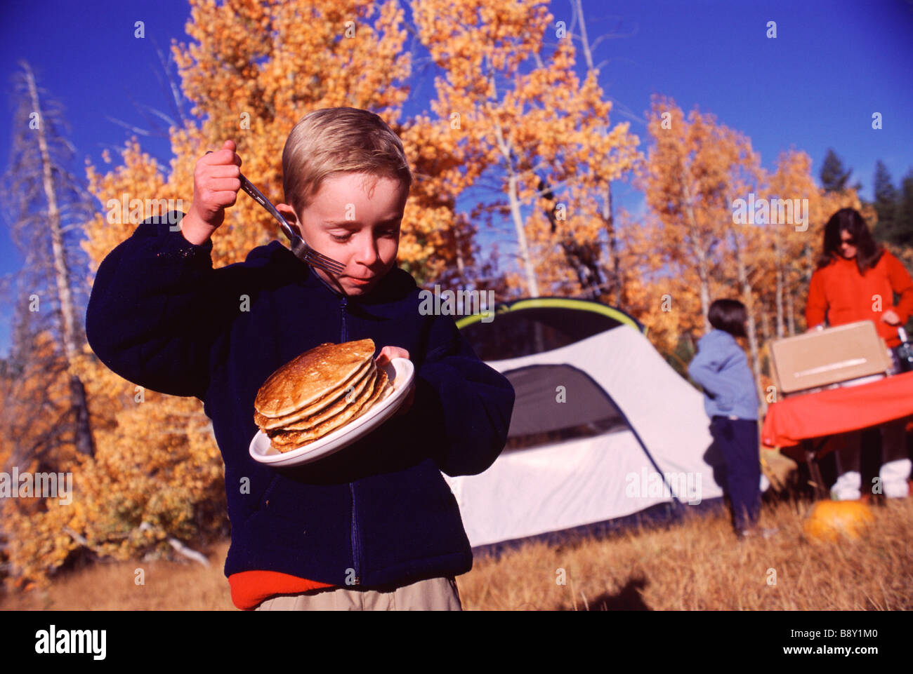 Boy holding a plate of breads and a fork while camping, Truckee, Nevada County, California, USA Stock Photo