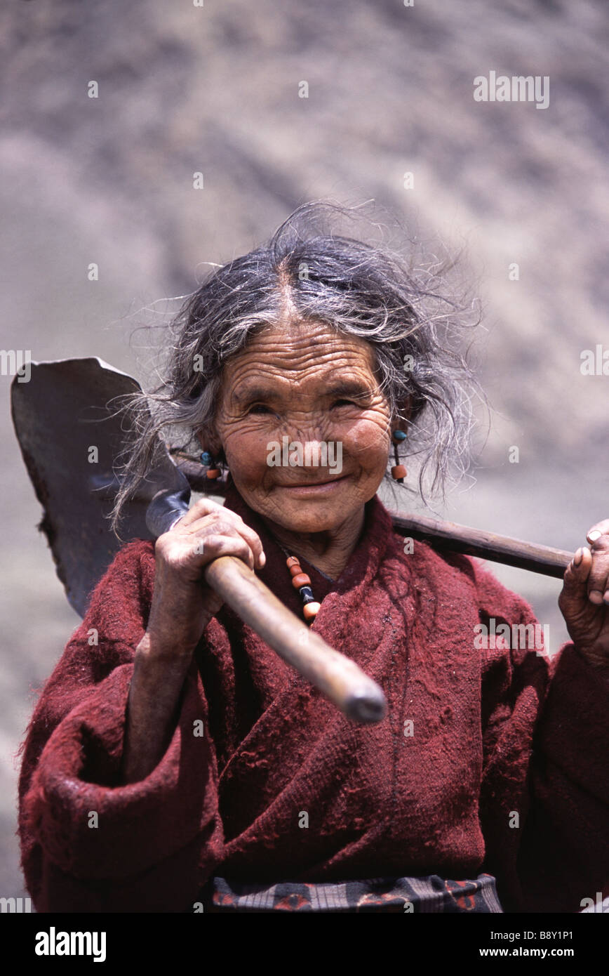 Portrait of a senior woman with a shovel on her shoulder, Samagaon Village, Nepal Stock Photo
