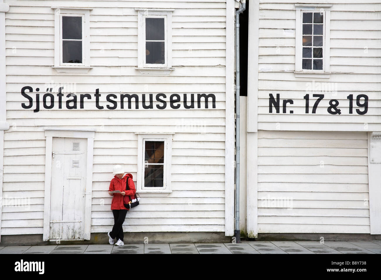 Woman leaning against the wall of a museum, Maritime Museum, Stavanger, Rogaland County, Norway Stock Photo