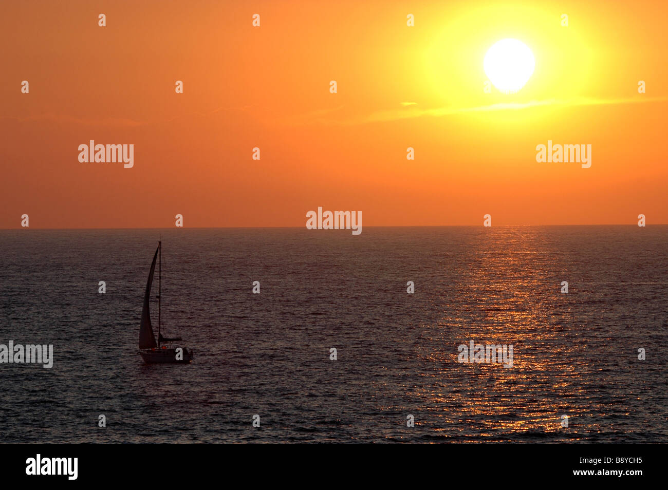 Sailboat and setting sun over ocean Island Menorca Balears Spain Stock Photo