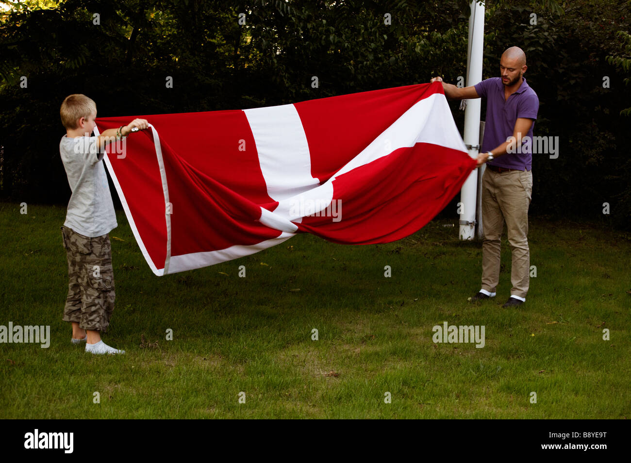 A man and a boy folding the Danish flag Copenhagen Denmark. Stock Photo