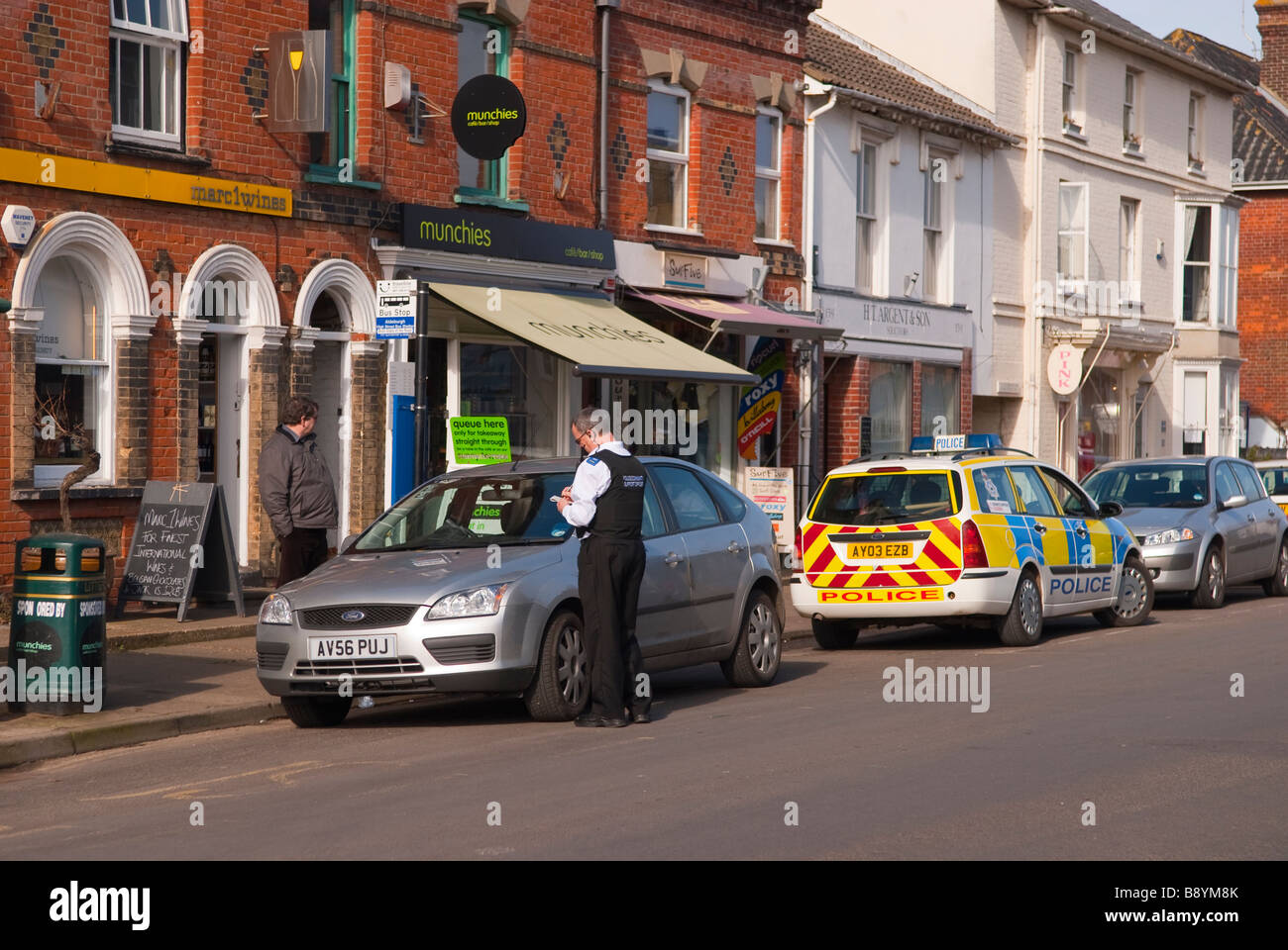 A police community support officer cso issuing a parking ticket on an illegally parked car in the uk Stock Photo