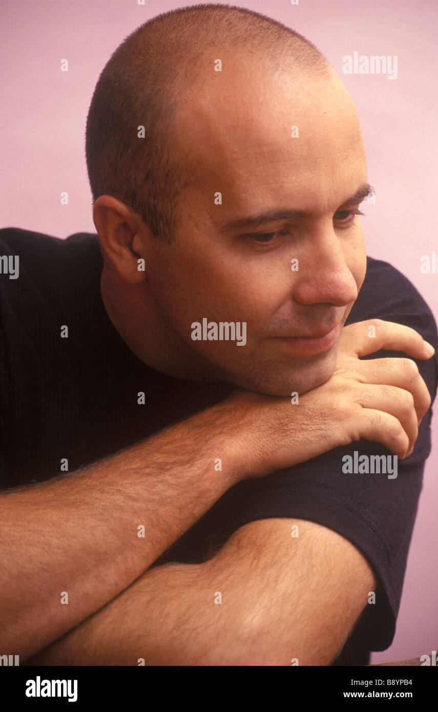 man with shaved head looking depressed and moody Stock Photo