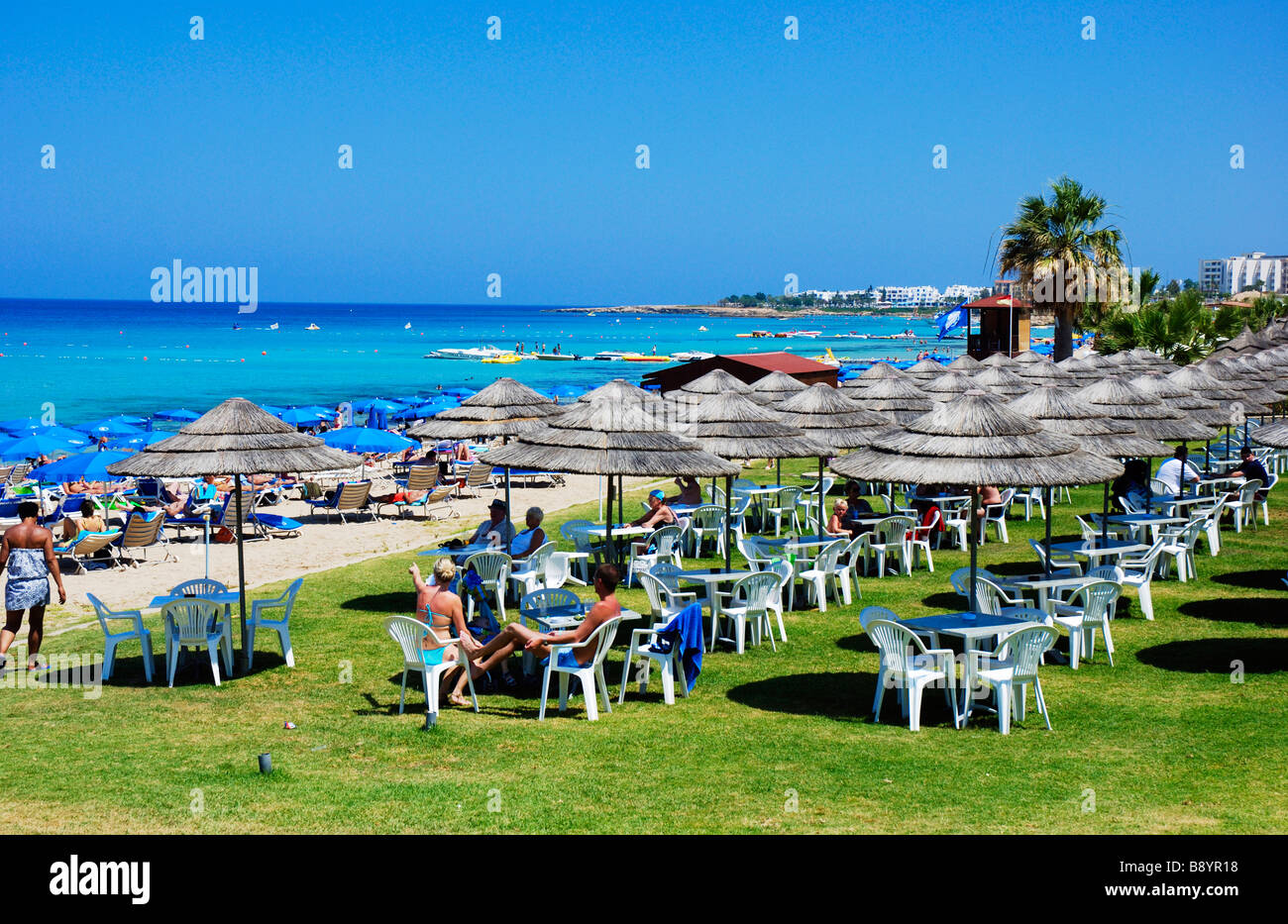 The lawn by the beach is a popular hangout for tourists in Protaras / Fig Tree Bay, Cyprus Stock Photo