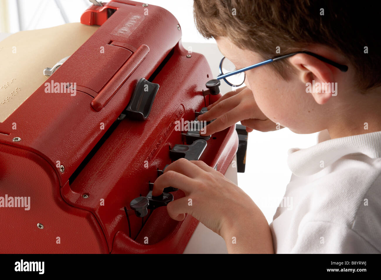 A visually impaired blind school boy struggling to use a braille machine brailler Stock Photo