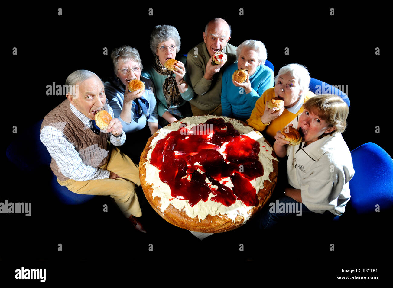OAP's from Torrington friendship club tucking in to a normal scone beside the world's biggest monster scone, Devon UK Stock Photo