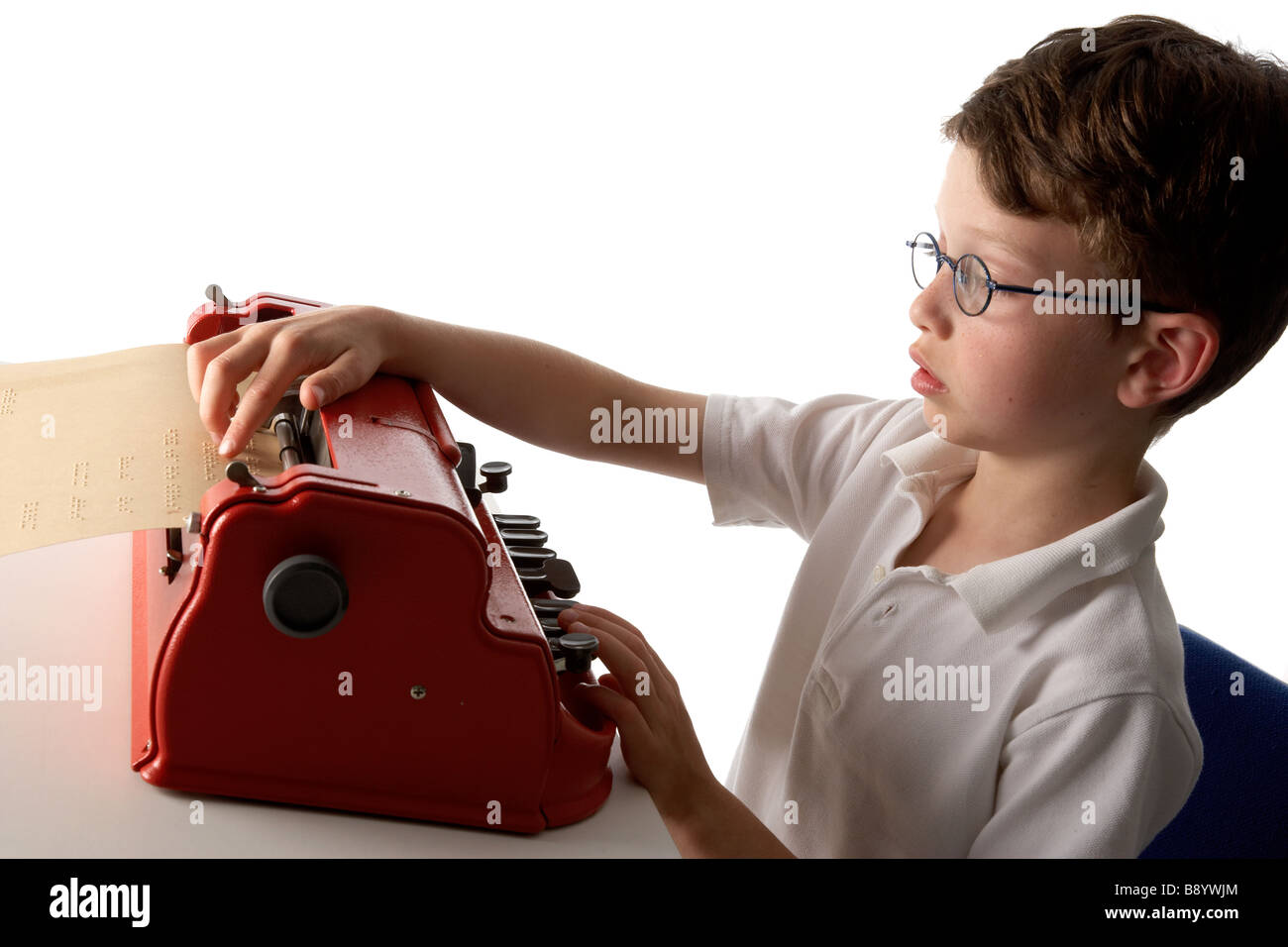 A visually impaired blind school boy struggling to use a braille machine brailler Stock Photo