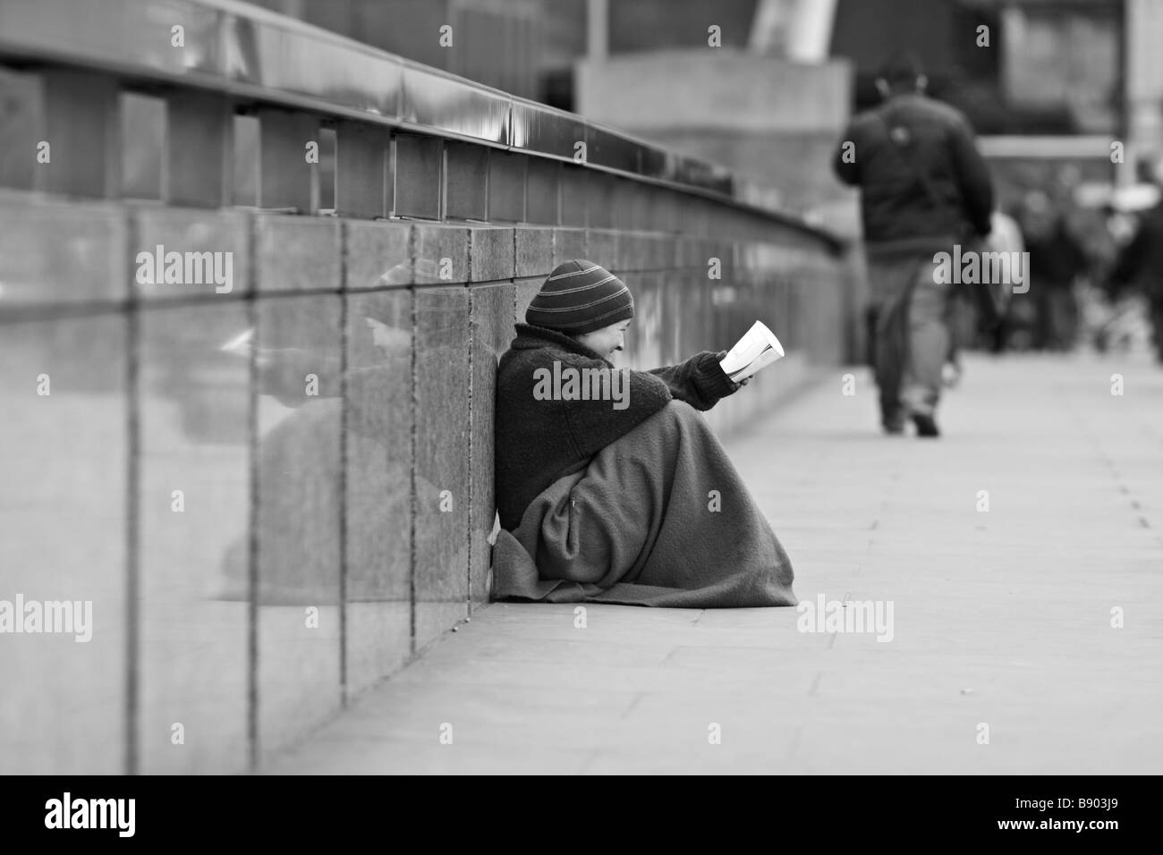 Homeless girl sitting on the London Bridge holding a cup for spare ...