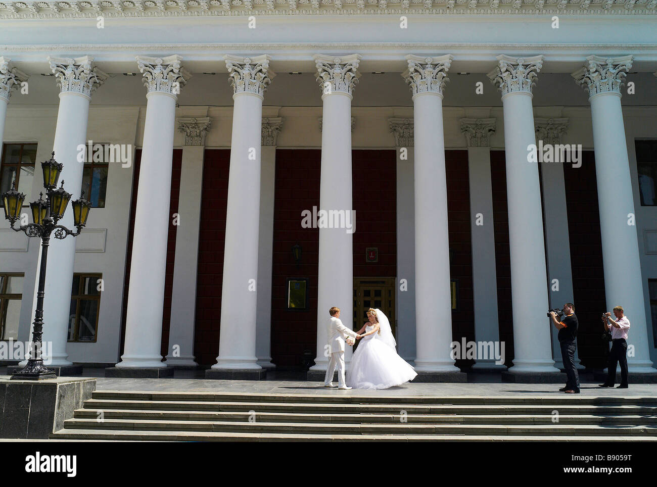 A bride and groom being filmed for their wedding day videoed outside the civic buildings in Odessa Ukraine Stock Photo