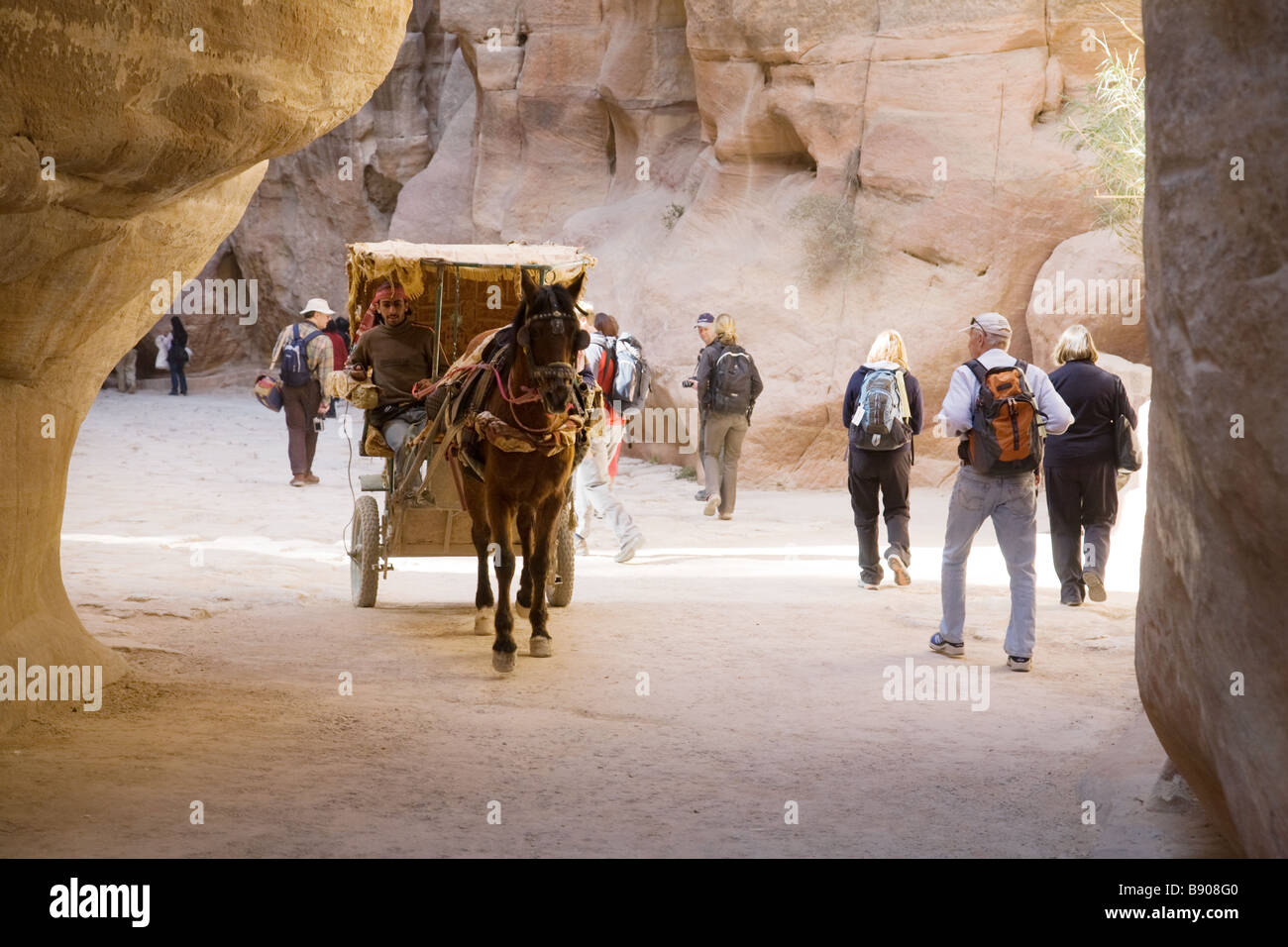 Tourists and a horse and cart in the Siq, the entrance to Petra, Jordan Stock Photo
