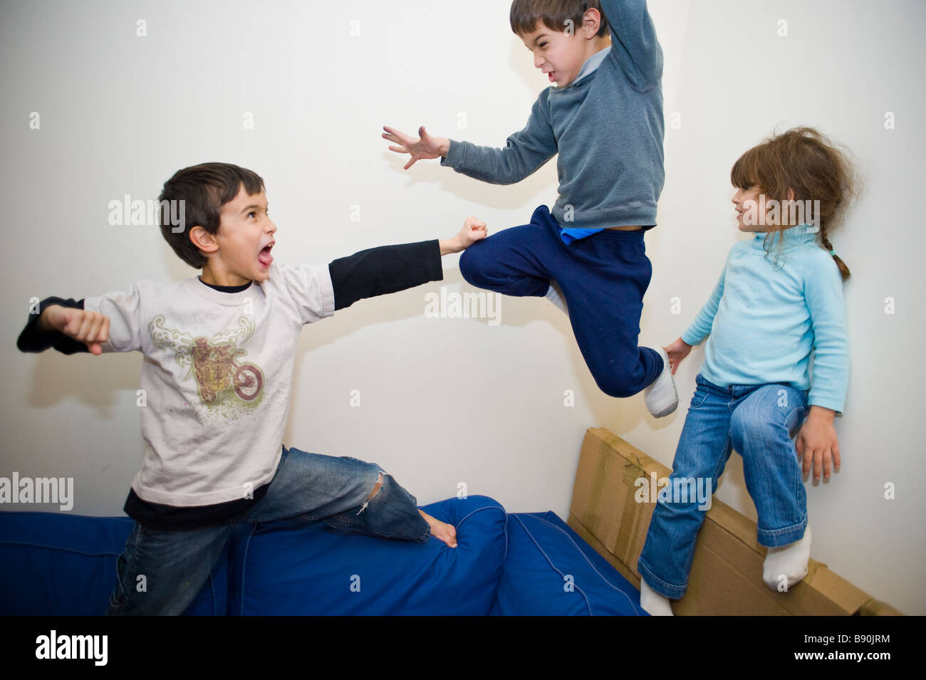Male children play fighting on the sofa Stock Photo