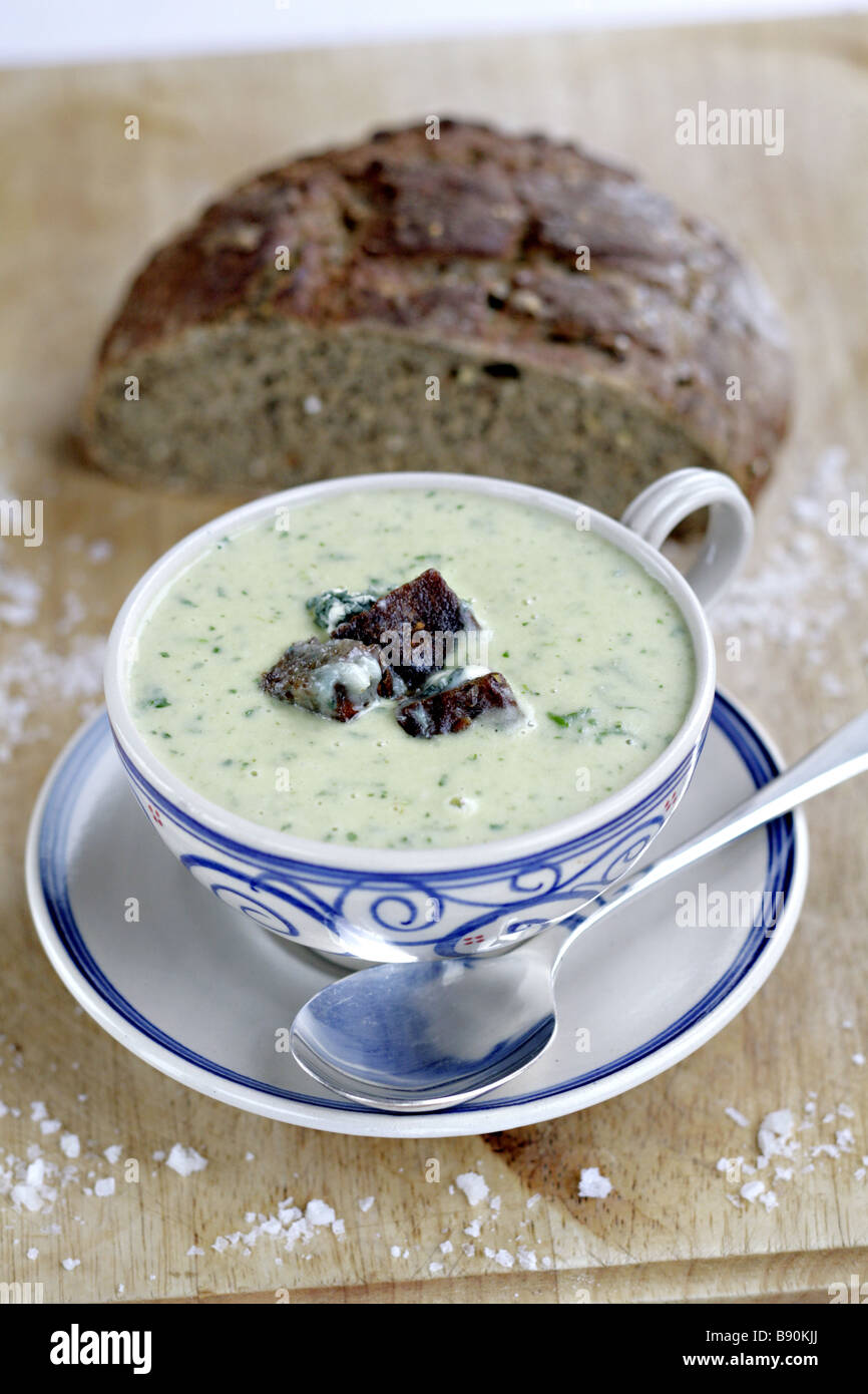 Potato Rocket Soup with blue cheese crutons on board with bread and rock salt Stock Photo