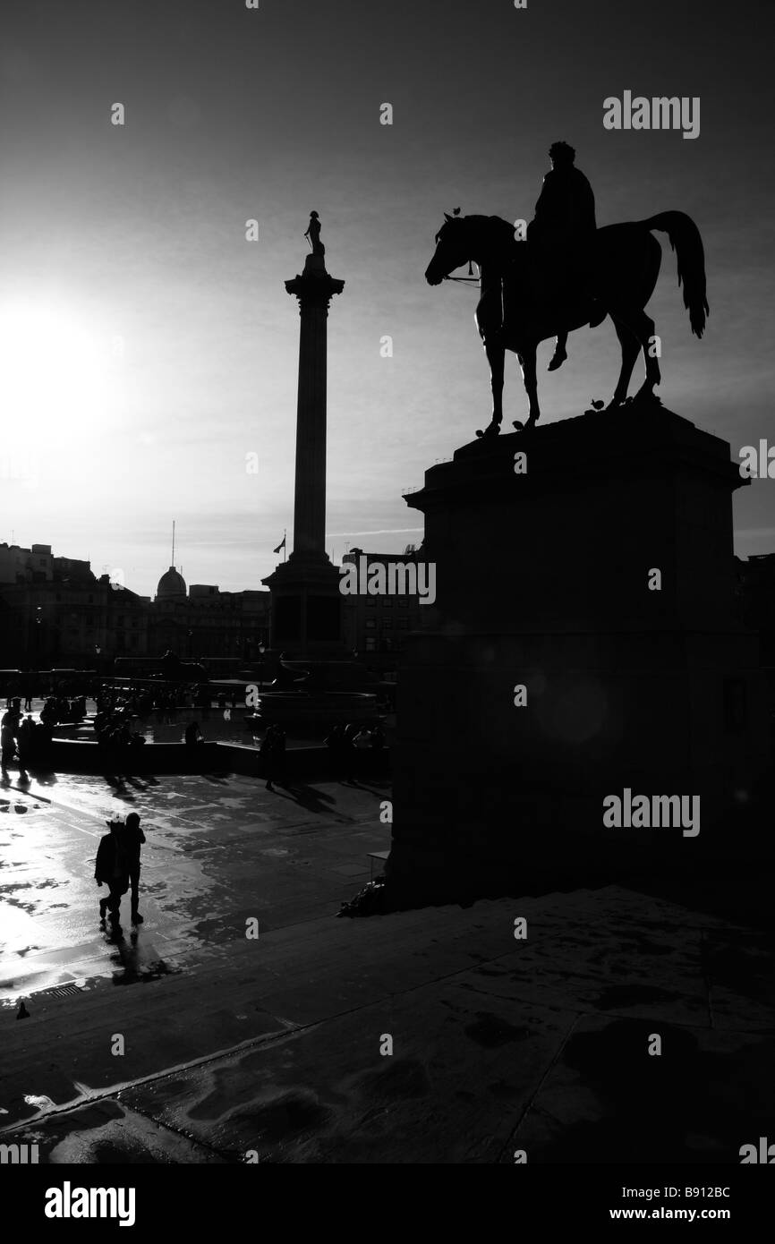 Statue of King George IV and Nelson's Column silhouetted by the low Winter sun, Trafalgar Square, London Stock Photo