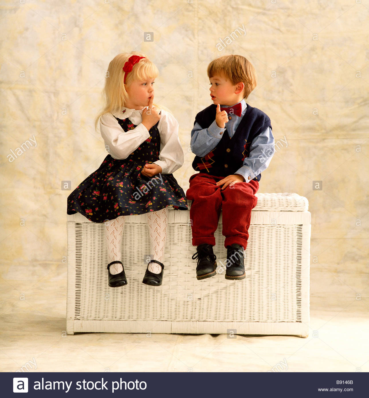 small boy and girl sitting together on a hamper stock photo