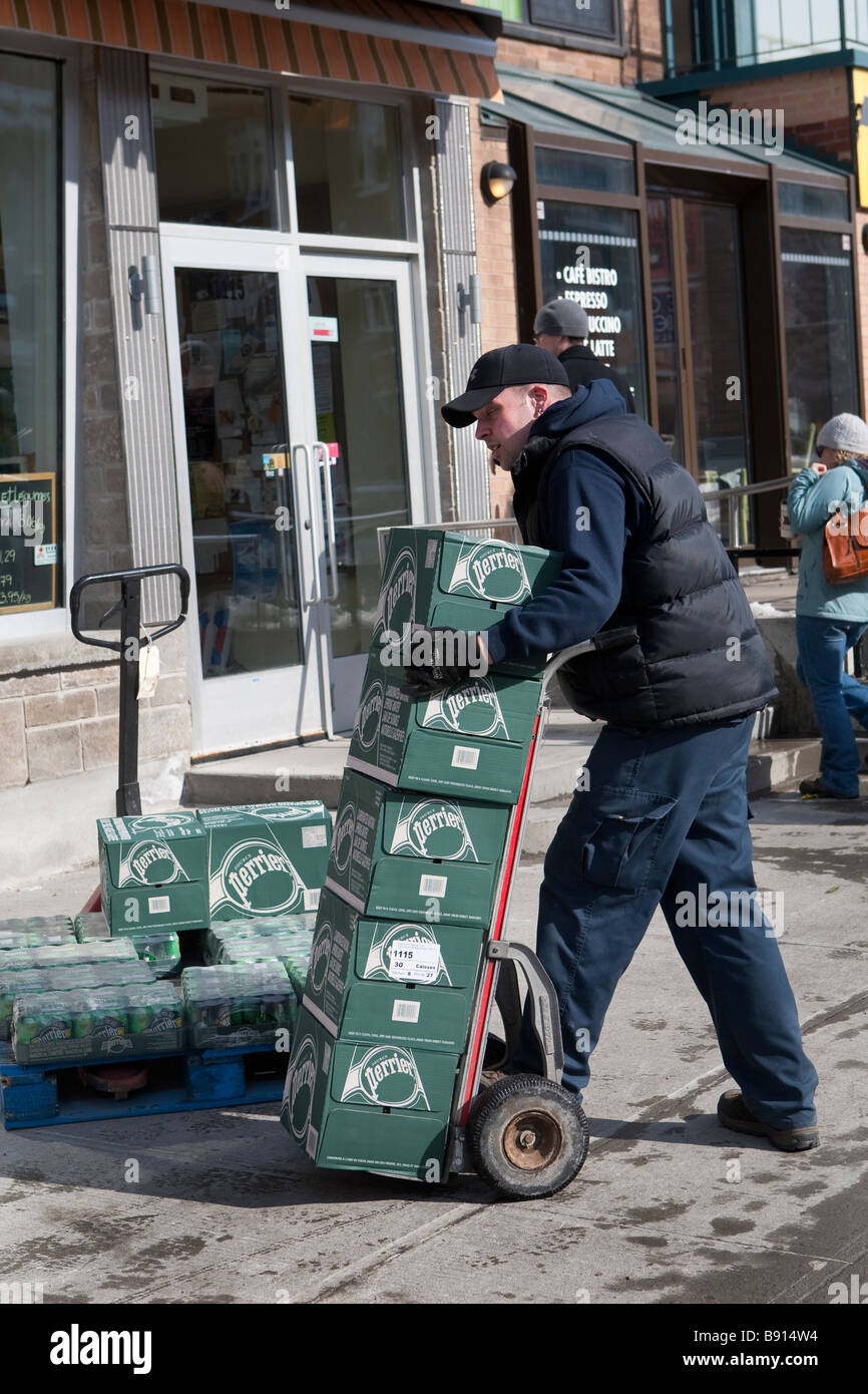 A man delivers boxes of Perrier water mineral bottles to a  grocery March 10 2009 Stock Photo