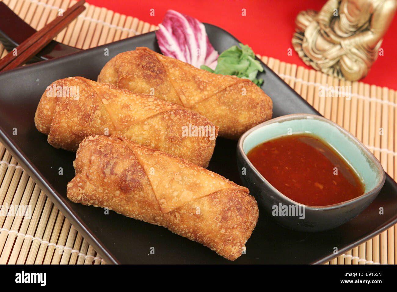 A plate of crispy fried egg rolls with spicy sweet chili sauce for