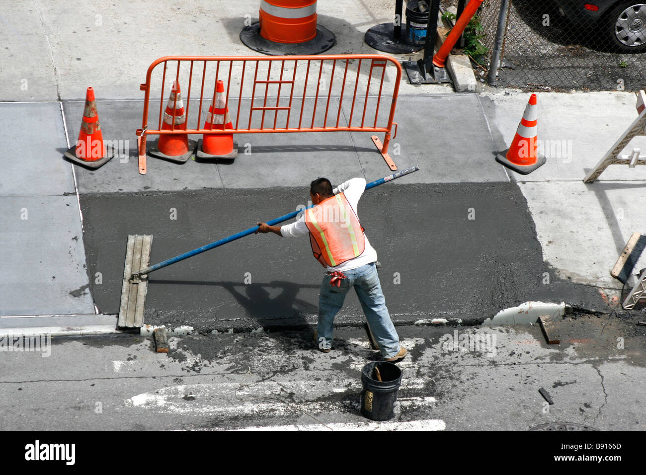 Man smoothing a freshly poured wet concrete sidewalk. Stock Photo